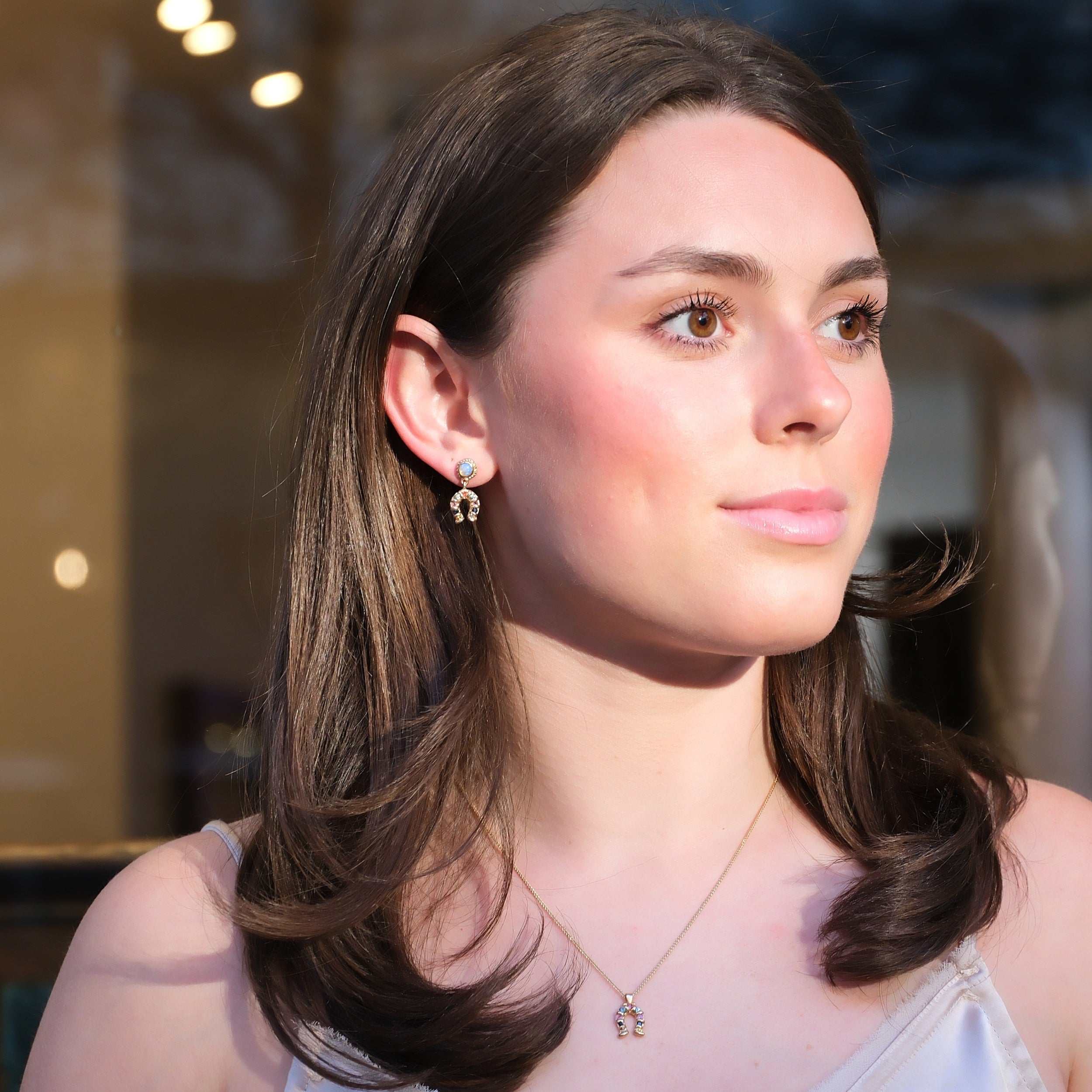 woman wearing 9k sapphire horseshoe earrings and necklace